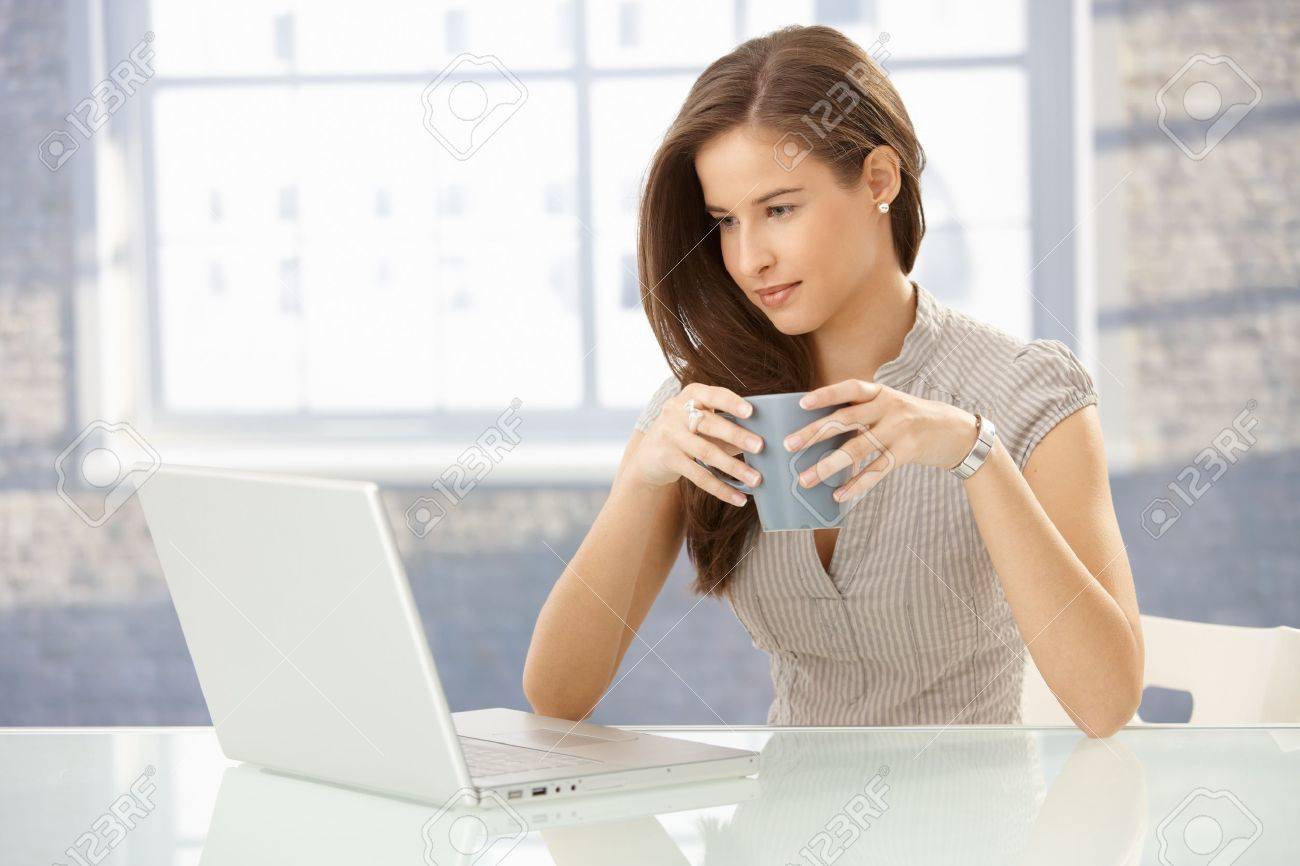 8604028-Beautiful-smiling-businesswoman-at-work-looking-at-laptop-computer-screen-having-tea--Stock-Photo.jpg